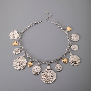 Detail of vintage silver chain necklace with coin medals and gold lucky heart charms