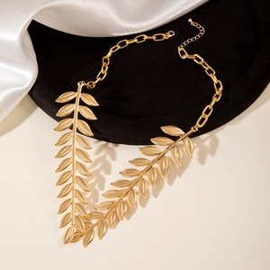 Macro detail of golden laurel leaf pendant with textured alloy finish on black velvet display