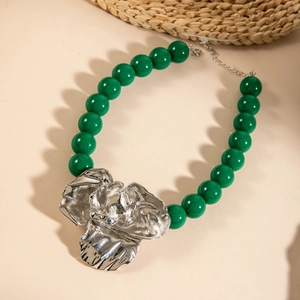 Detail of green acrylic beads and silver flower pendant with rustic textured finish