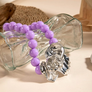 Close-up of bright purple acrylic beads and a large silver metallic floral pendant necklace