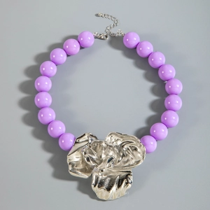 Macro detail of purple chunky beads with an artistic irregular silver flower pendant