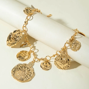 Detailed close-up of retro chunky gold bracelet with hammered charms on display stand