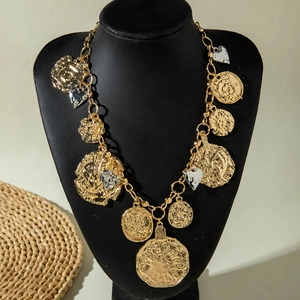 Close-up of vintage chunky gold chain necklace with embossed coin and heart charms