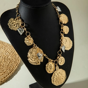 Detail of vintage chunky necklace with gold alloy coins and silver heart pendants