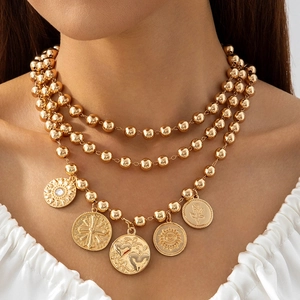 Detail of bohemian gold multi-layer bead necklace with vintage coin pendants on a model