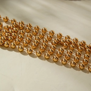 Detailed close-up of multilayered golden beaded chains with polished mirror finish