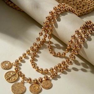 Detailed close-up of retro gold beaded necklace with five embossed floral coin pendants