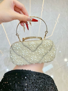 Close-up of pearl flower clutch bag with crystal edges and gold metal ring handle