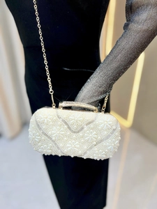 Detailed view of pearl floral pattern evening clutch with diamond handle and gold chain