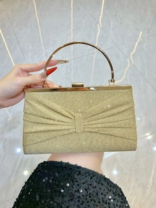 Close-up of golden pleated evening bag with sparkling glitter and metal ring handle
