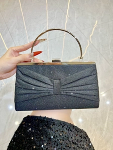 Macro shot of black glitter clutch bag with bow detail and round metal handle