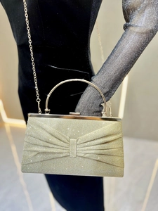 Detail of elegant gold glitter clutch with bow-shaped pleats and metallic handle