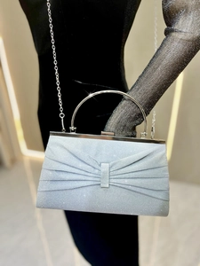 Sparkly silver evening clutch bag with pleated bow and chic metal handle worn by model