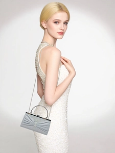 Detail of silver pleated evening clutch with round metal handle and shimmering texture