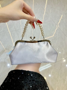 Detail of silver satin evening bag featuring pearl handle and blue lace trim