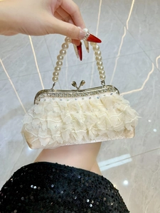 Close-up of pearl handle and rhinestone metal frame on ivory lace evening handbag