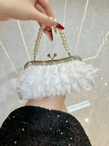Detail of white lace evening bag featuring sparkling sequins and elegant pearl handle