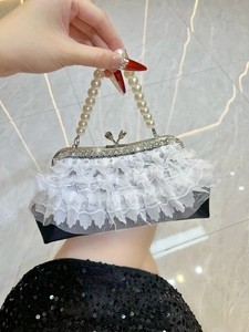 Detail of white lace layers on black party bag with pearl handle and rhinestone lock
