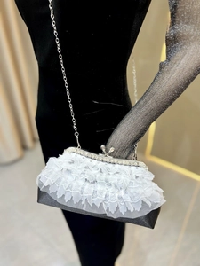 Detailed shot of white lace evening bag with rhinestones and silver metal chain strap