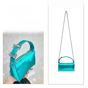 Detail of teal satin clutch bag with rectangular rhinestone buckle and silver metal chain