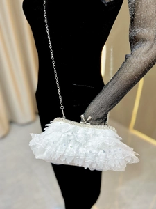 Detail of white lace evening clutch with rhinestones, silver metal frame and kiss-lock