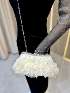 Detail of off-white lace evening clutch with rhinestones and silver metal chain strap