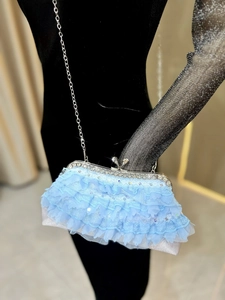 Close-up of light blue lace evening bag with sparkling rhinestones and silver chain strap