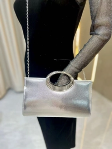 Detail of silver evening clutch with textured finish and rhinestone handle on shoulder