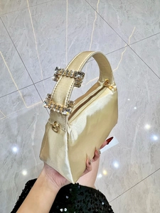 Detail of champagne satin evening bag featuring sparkling rhinestone handles and metal zipper
