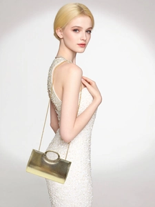 Detail of elegant gold evening clutch bag with sparkling rhinestone circle buckle on white dress