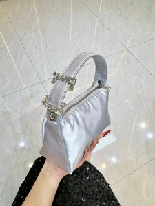 Elegant silver satin evening bag with sparkling rhinestone buckles shown in hand