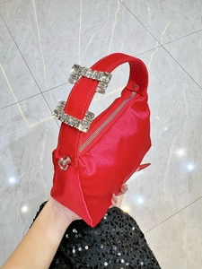 Close-up of red satin evening bag with luxury rhinestone buckles on the top handle