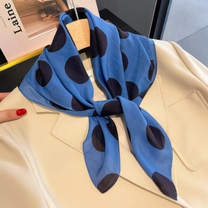 Foulard quadrato di seta blu a pois su giacca beige per un look da ufficio elegante