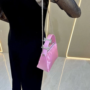 Close-up of pink satin shoulder bag featuring elegant rhinestone buckles and metal chain