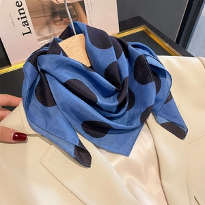 Foulard estivo in seta a pois classici presentato su un elegante blazer beige