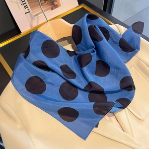 Elegante foulard in seta blu navy a pois su un blazer beige per un look vintage raffinato