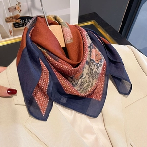 Retro silk square scarf with geometric and floral prints styled on a beige suit