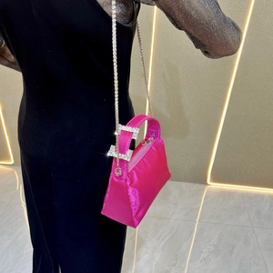 Detail of rose pink satin handbag with sparkling rhinestone buckles and silver chain strap