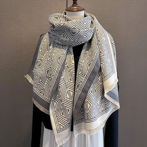 Winter grey and white geometric plaid cashmere scarf with fringes on a mannequin