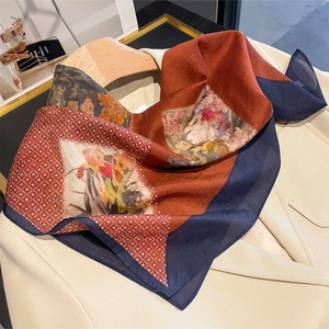Vintage floral silk scarf with geometric patterns on a hanger over a beige blazer