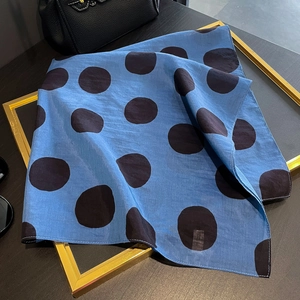 Elegante sciarpa di seta quadrata a pois blu da donna su una superficie nera