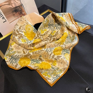 Elegant silk-like square scarf with bright yellow sunflower print on a black coat