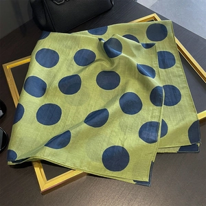 Foulard in seta verde a pois blu scuro esposto in una cornice dorata di lusso