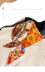 Detailaufnahme eines Seidenschals mit Blumenmuster, gestylt auf einem beigen Blazer