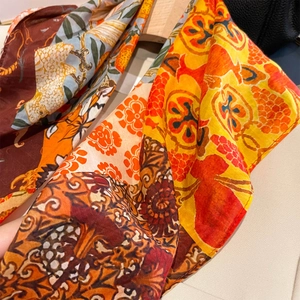 Vintage Seidenschal mit Blumenmuster in leuchtenden Farben an einem Holzbügel
