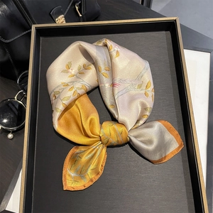 Close-up of silk square scarf featuring retro floral bird print and satin texture