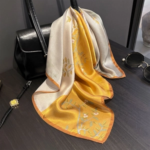 Detail of floral silk scarf tied on a handbag with satin sheen and yellow grey patterns