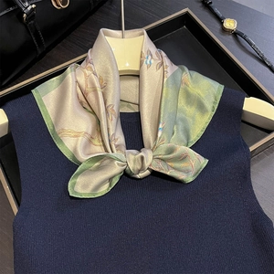 Detail of elegant silk neck scarf with floral pattern on a navy knit sweater