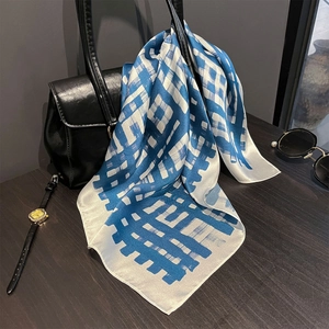 Blue striped 100% mulberry silk scarf draped elegantly on a black leather designer handbag