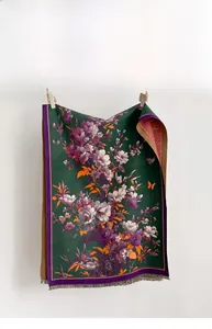 Detail of dark green scarf showing purple floral patterns and elegant gray tassels
